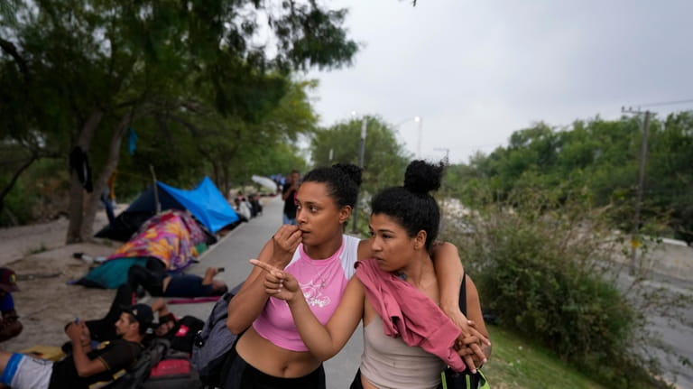 Venezuelan migrant women stand on the banks of the Rio...