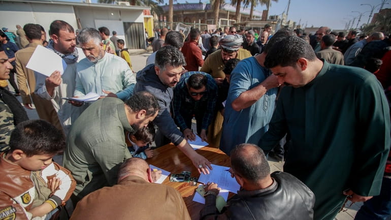 Supporters of the Shiite cleric Muqtada al-Sadr sign a pledge...