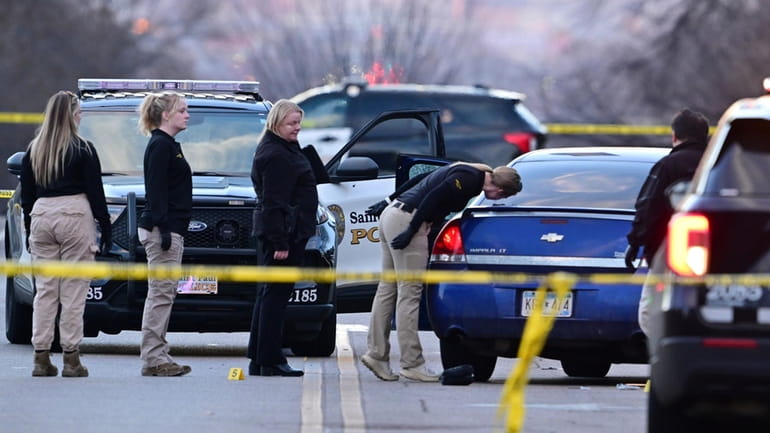 Investigators examine a car with a broken door window at...