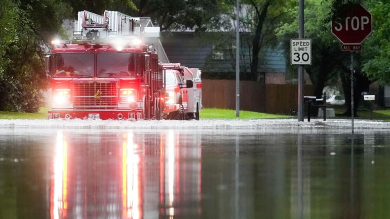 A Houston firetruck makes it way through flood water in...