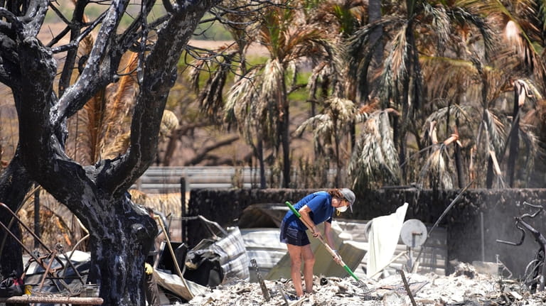 A woman digs through rubble of a home destroyed by...