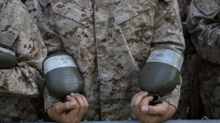 A U.S. Marine Corps recruit holds two canteens of water...