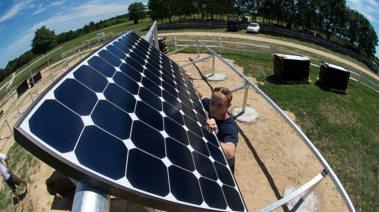 Danny Volkomer, an installer with Green Logic, installs a solar...