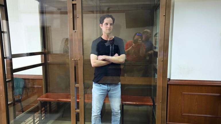 Wall Street Journal reporter Evan Gershkovich stands in a glass...