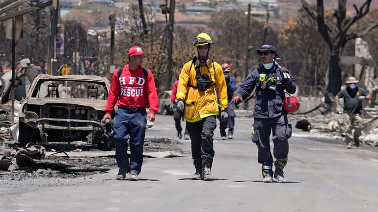 Members of a search-and-rescue team walk along a street, Saturday,...