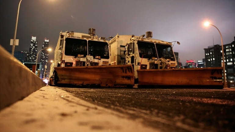 FILE — Sanitation trucks mounted with snow plows are parked...