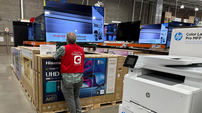 An associate checks over a big-screen television on display in...