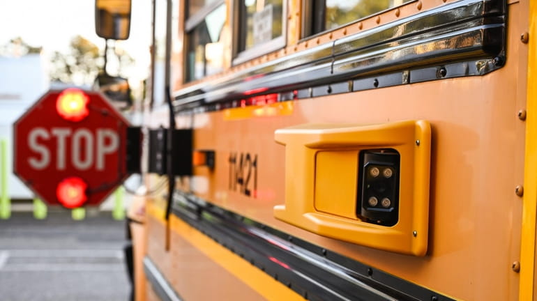 A school bus displays an extended flashing stop sign.