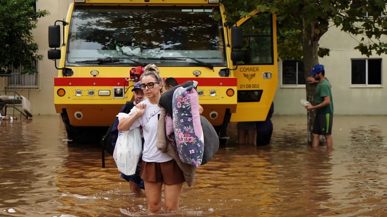 Residents evacuate from a neighborhood flooded by heavy rains, in...