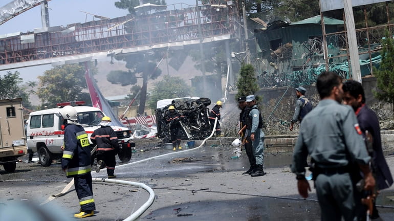 Afghan fire fighters extinguish vehicles on fire after an attack...