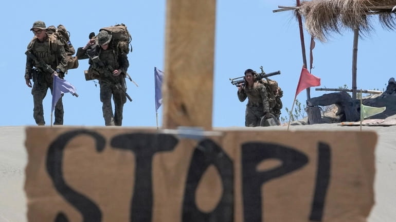 U.S. troopers in battle gear walk under the scorching sun...