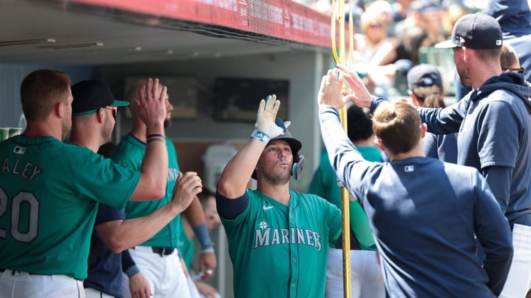 Seattle Mariners' Ty France, center, holds a trident in the...