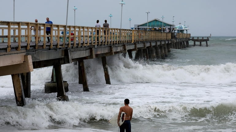 A surfer enters the water near Anglin's Fishing Pier as...