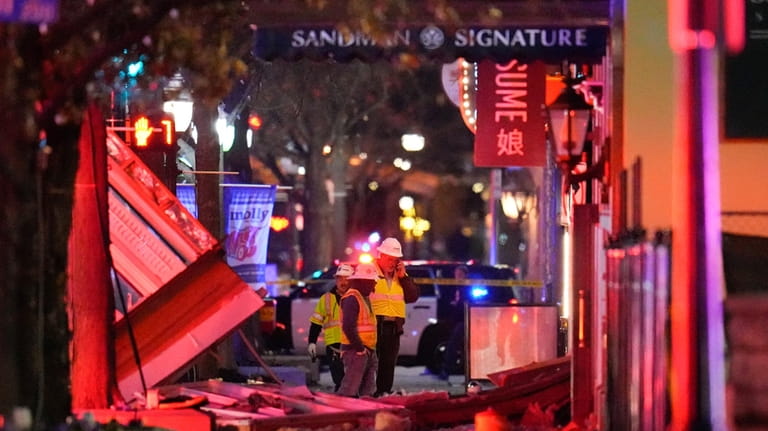 Workers survey damage near the Sandman Signature hotel following an...