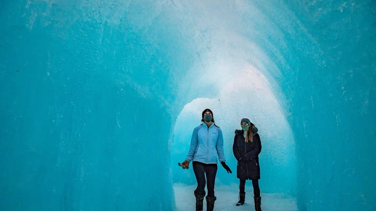 People walk through an ice tunnel as they explore the...