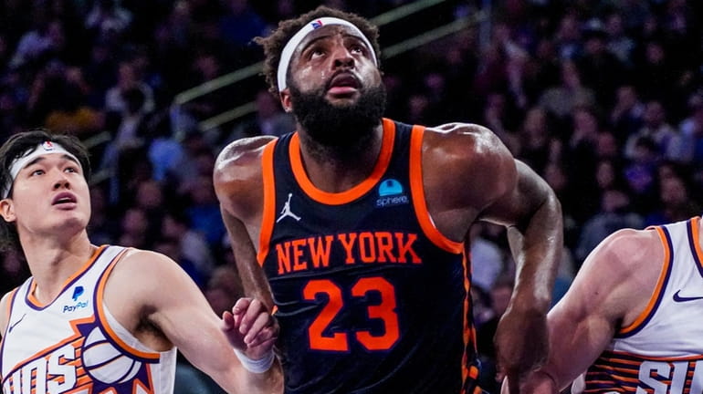Knicks center Mitchell Robinson fights for rebounding position against Suns...
