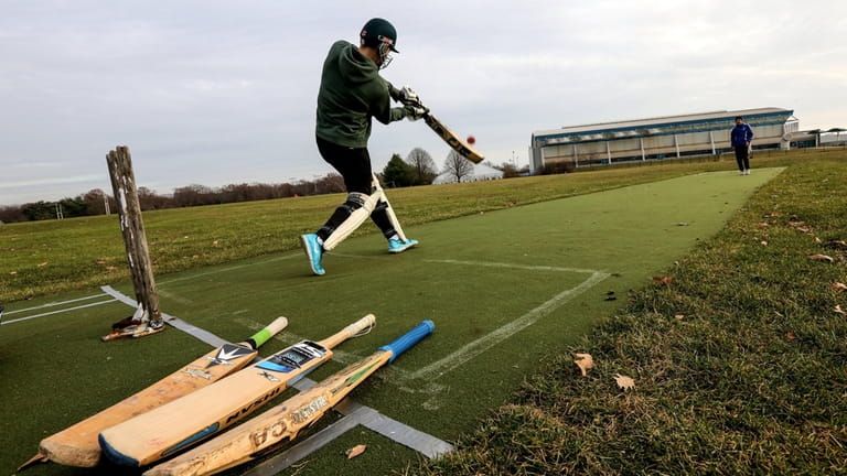 A cricket player practices hitting at Eisenhower Park.