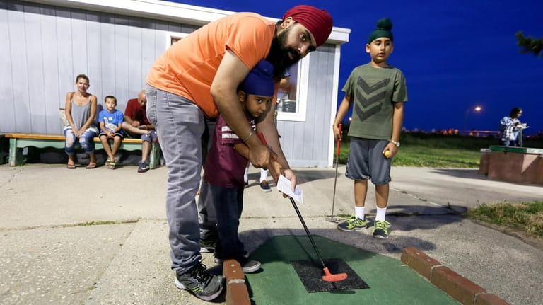 Yugnik Singh, helps his son, Saveer, at the mini-golf course...