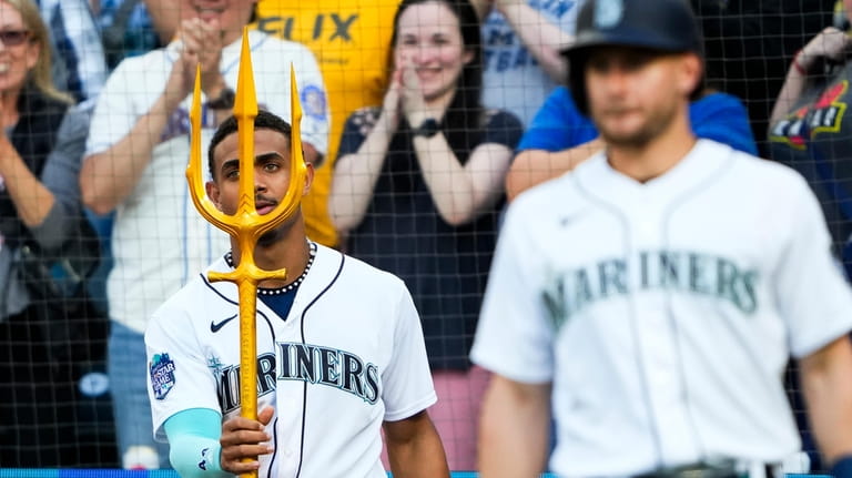 Seattle Mariners' Julio Rodriguez, left, holds a trident as he...