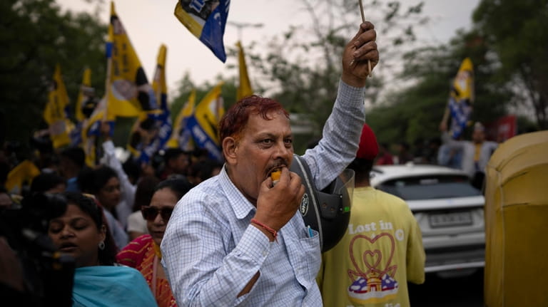 A supporter of the Aam Aadmi Party eats a sweet...