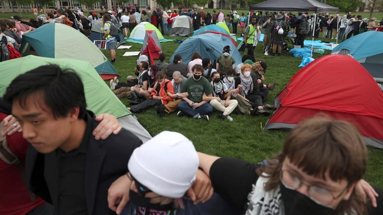 Pro-Palestinian protesters link arms around campers as police show up...
