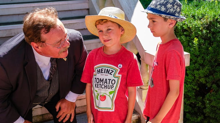 Joe Wiegand, as Teddy Roosevelt, chats with twins John, center, and...