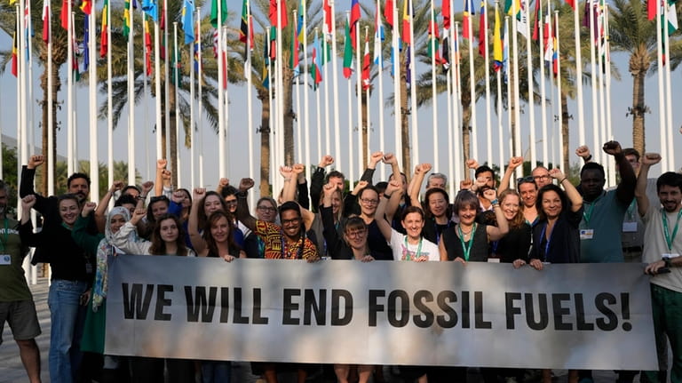 Members of Greenpeace gather for a photo around a sign...
