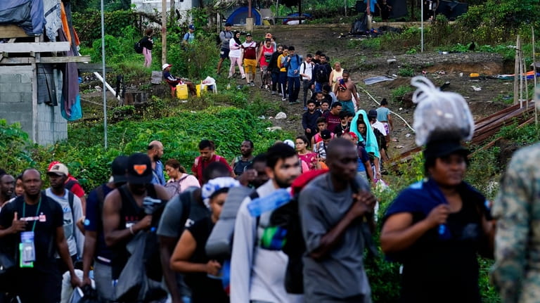 Migrants heading north line up to take a boat, in...