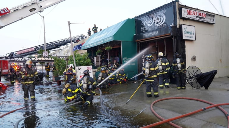 Long Beach firefighters pour water on a row of stores on West Park...