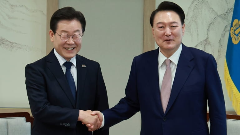 South Korean President Yoon Suk Yeol, right, shakes hands with...