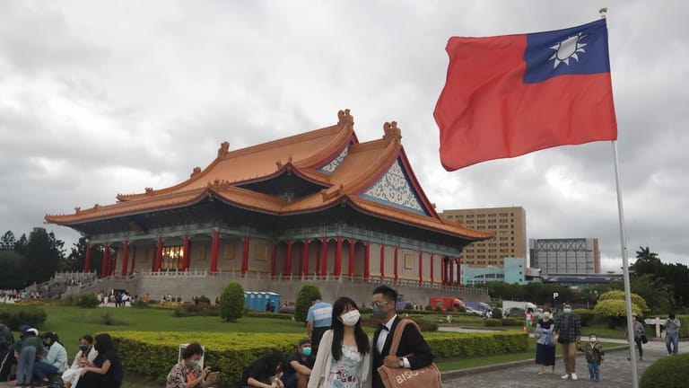 People wearing face masks walk around the Chiang Kai-shek Memorial...
