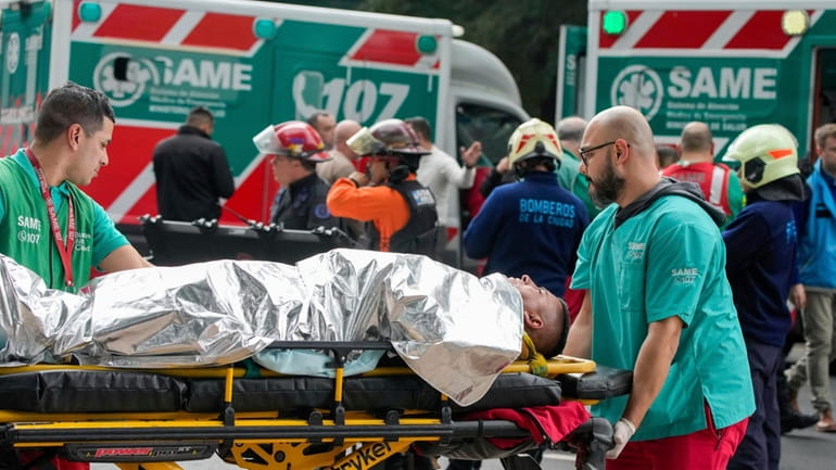 Paramedics transport injured commuters after two trains collided in Buenos...