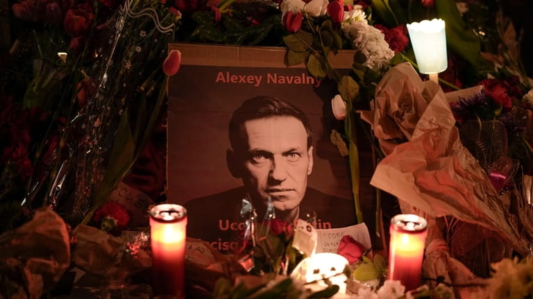 Flowers and candles are laid around a photo of Russian...
