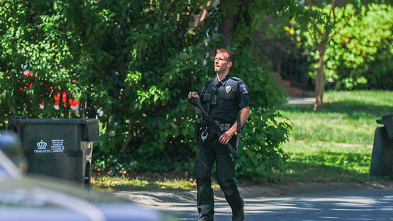 A Charlotte Mecklenburg police officer carries a gun as he...