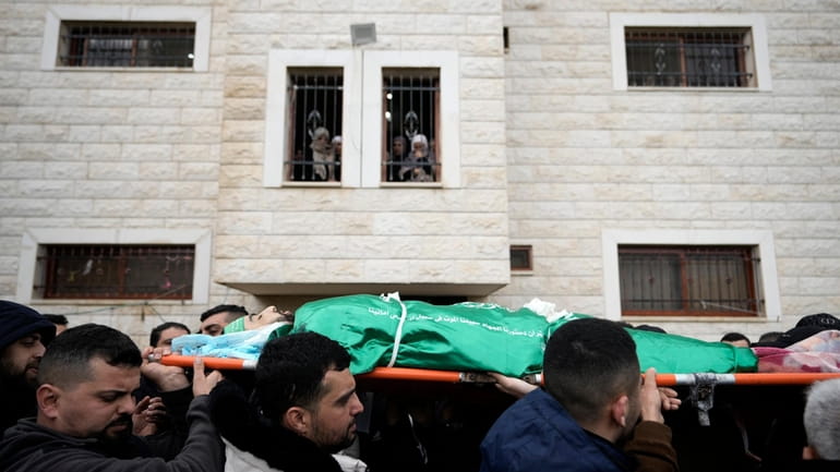 Palestinian mourners carry the body of Muhammad Jalamneh, draped in...