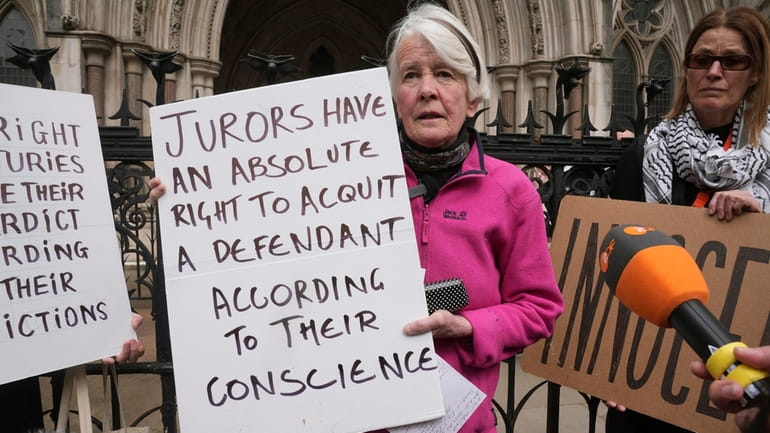 Protester Trudi Warner holding a sign outside the Royal Courts...