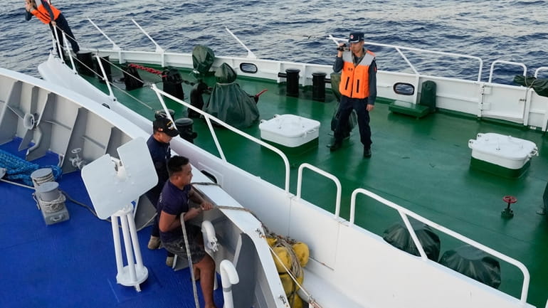 Philippine coast guard crew on BRP Sindangan lower their rubber...