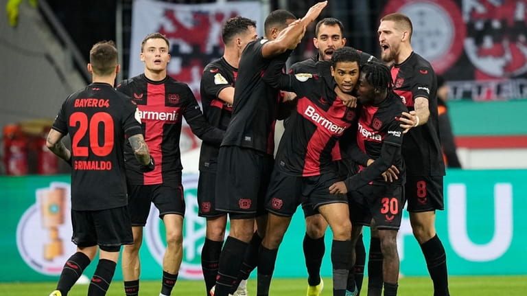 Leverkusen's Amine Adli, center, celebrates with team mates after scoring...