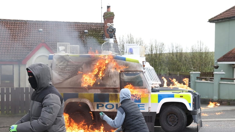 Masked youths throw petrol bombs at a police Land Rover...