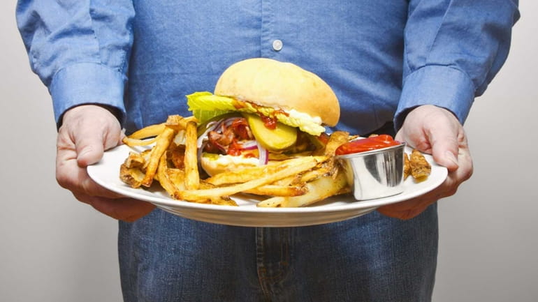 A man carrying a burger and fries. 