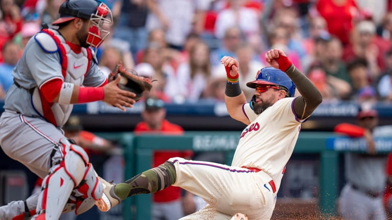 Philadelphia Phillies' Kyle Schwarber, right, slides into home on a...