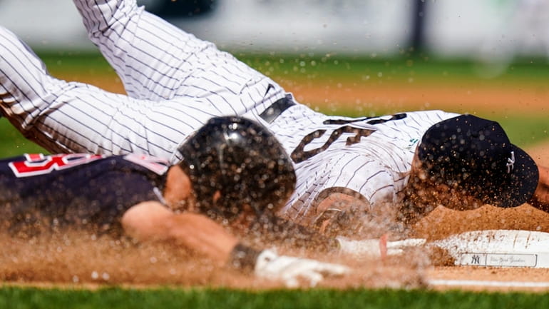 Yankees starting pitcher Nestor Cortes, right, dives to beat Cleveland...