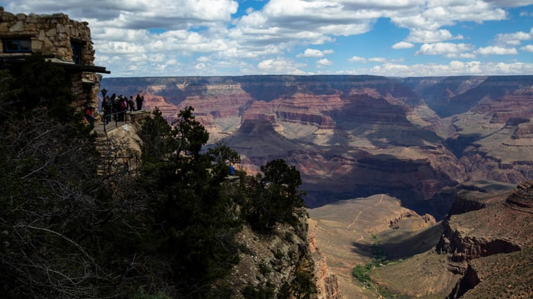 Tourists look out from the South Rim at the Grand...