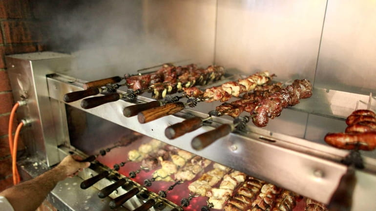 Rodizio skewers of chicken, steak and pork are grilled at...