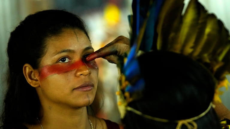 An Indigenous model paints the faces of other models during...