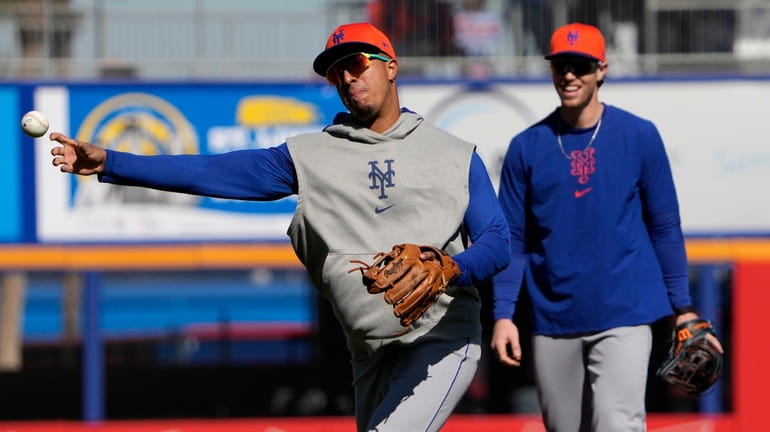 The Mets' Mark Vientos, left, throws as Brett Baty watches...