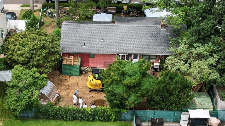Police and crime scene investigators dig in the backyard at...