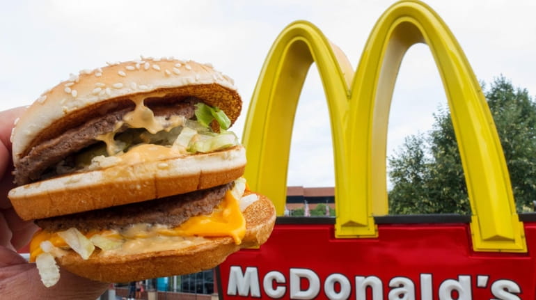 A McDonald's Big Mac, held up near the golden arches at...
