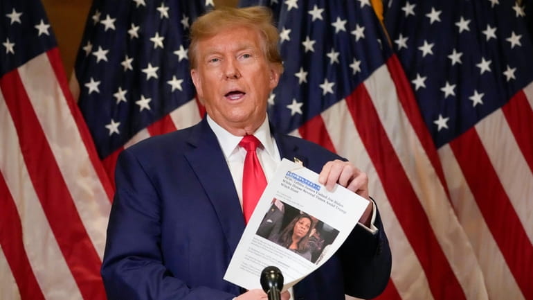 Former President Donald Trump holds up a copy of a...