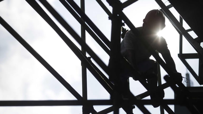 A construction worker sets up scaffolding.